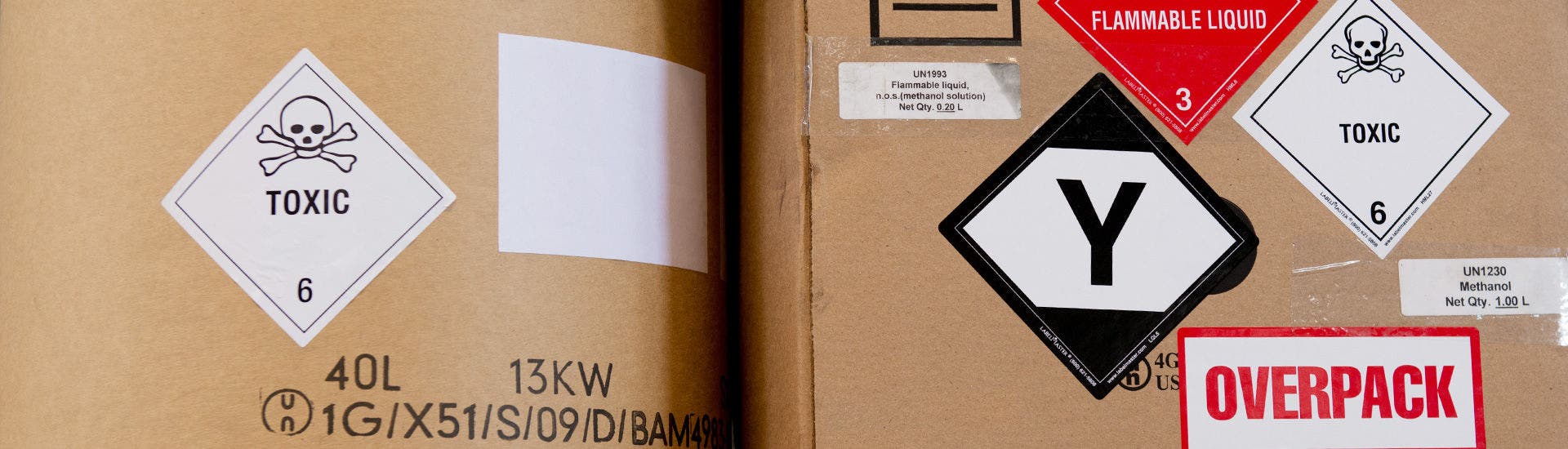Caixa de cartão com etiquetas e rótulos de segurança colados, com a indicação de que se trata de uma embalagem de transporte de mercadorias perigosas.