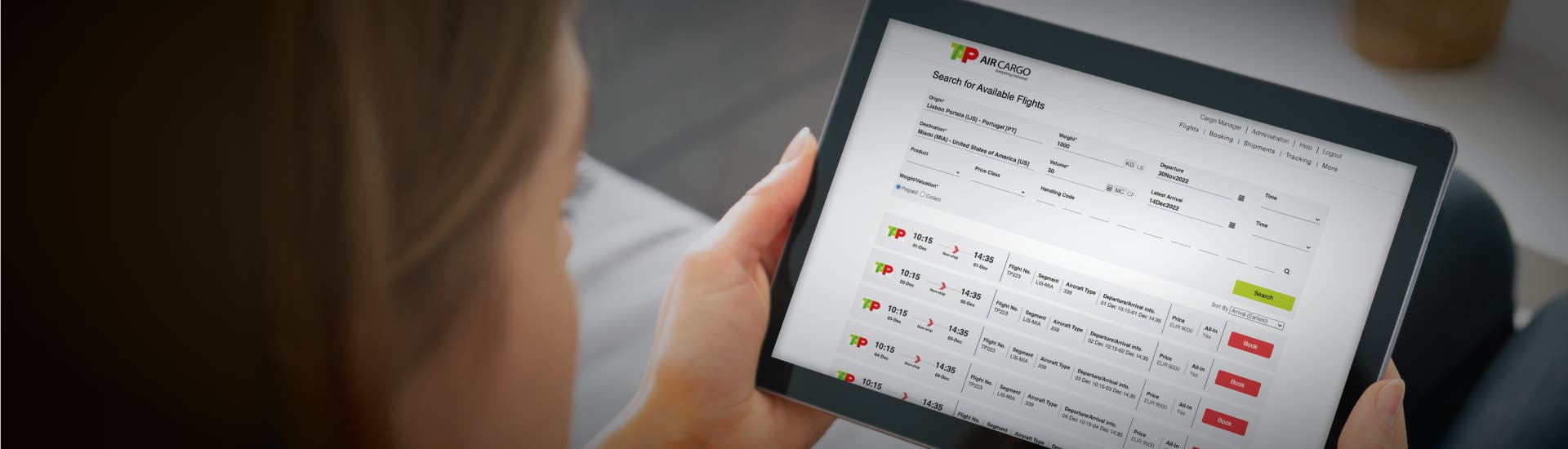 A tablet screen displaying the TAP Air Cargo page. A woman holds the device in her left hand. The background is blurred.